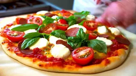 Toppings being put on pizza