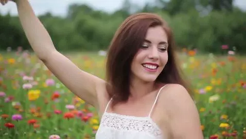 Woman with brown hair dancing in a meadow with c